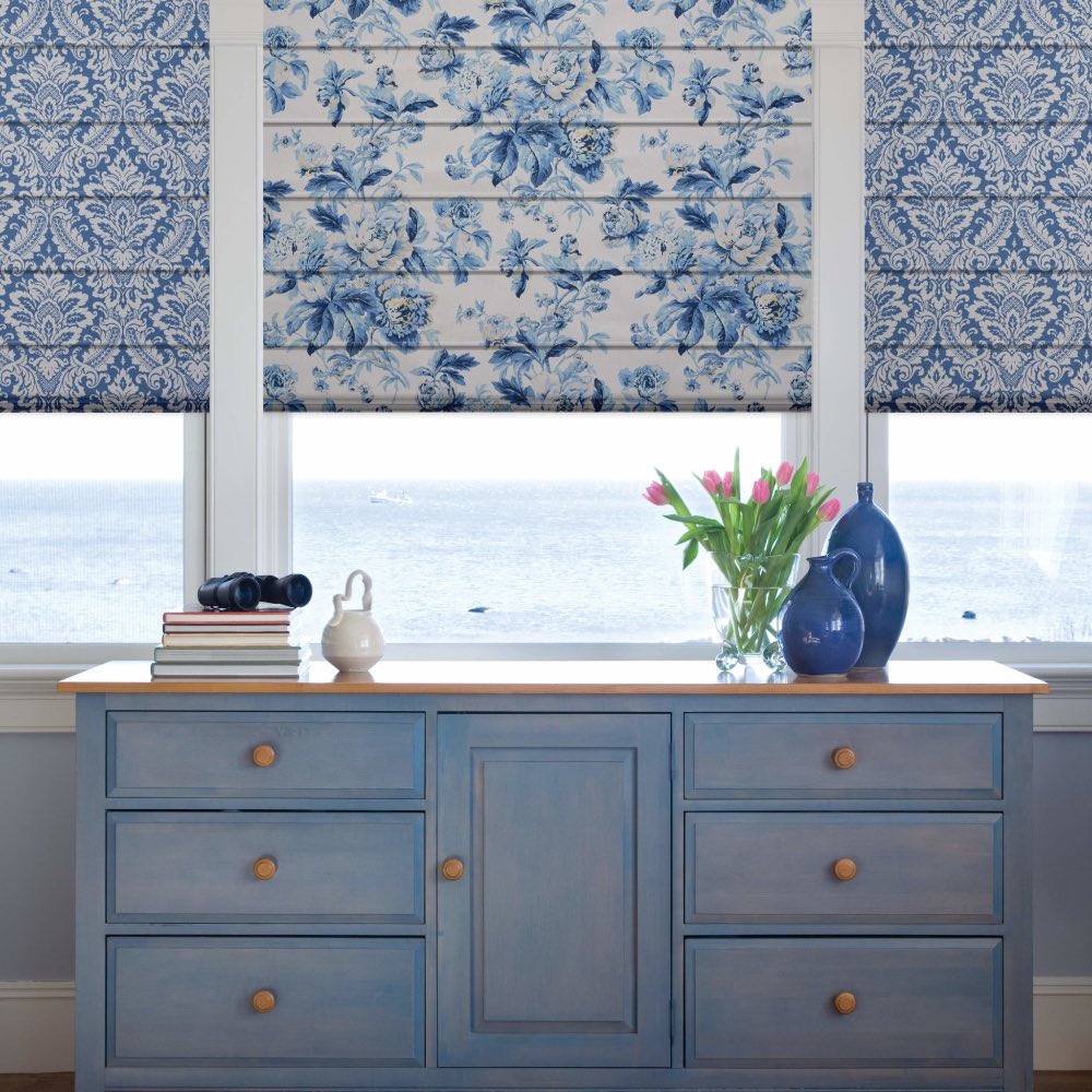 Patterned Roman shades above a dresser