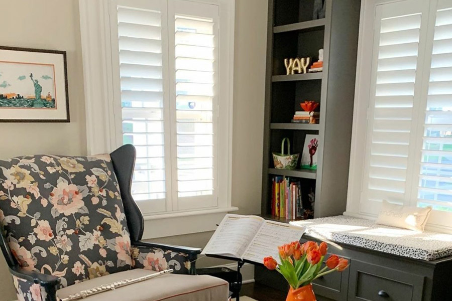 Elegant Polywood interior shutters are beneficial and stylish in a cozy home library. Photo credit: MeaghanBMurphy White Polywood shutters in a cozy and small living room with a bookshelf in the corner.