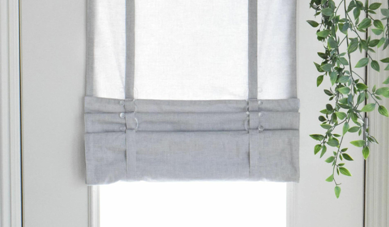 With a tiered tumble shade in Fort Myers, you can block sun glare all year round. Gray rolled tumble shade on a glass door